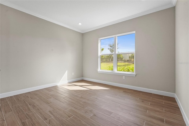 spare room with ornamental molding, light wood-type flooring, and baseboards