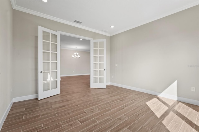 empty room with visible vents, french doors, ornamental molding, wood finish floors, and a chandelier