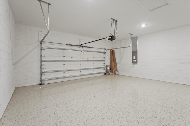 garage featuring concrete block wall, electric panel, and a garage door opener