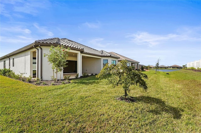 view of property exterior featuring stucco siding, a tiled roof, and a yard