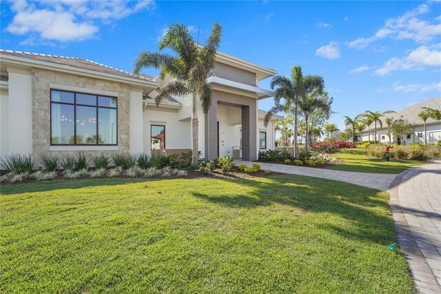 view of front facade with stone siding, stucco siding, decorative driveway, and a front yard