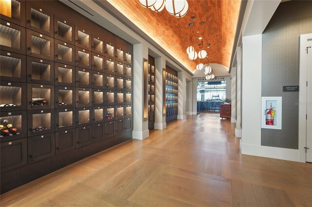 wine area with vaulted ceiling, wallpapered walls, parquet floors, and baseboards