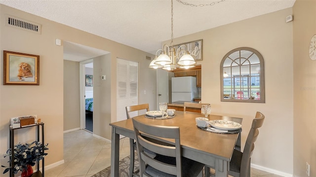 tiled dining space featuring a notable chandelier and a textured ceiling