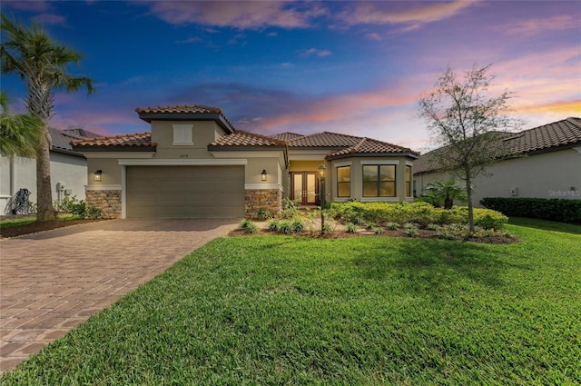 mediterranean / spanish house with stone siding, decorative driveway, and stucco siding