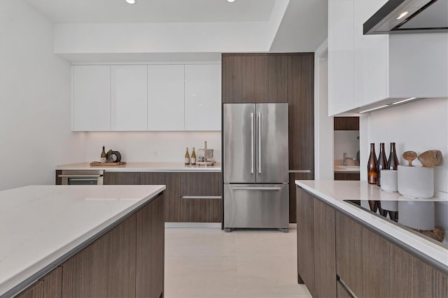 kitchen featuring white cabinetry, black electric cooktop, extractor fan, and stainless steel refrigerator