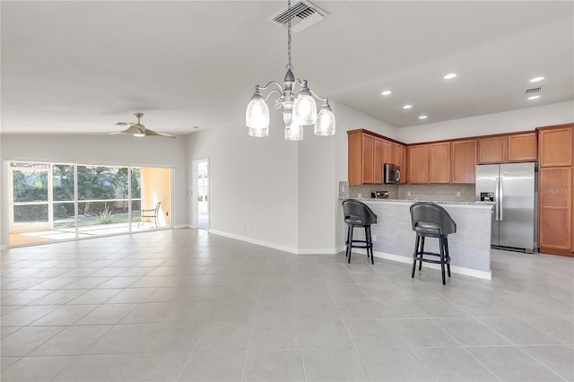 kitchen featuring a breakfast bar, tasteful backsplash, hanging light fixtures, light tile patterned floors, and stainless steel appliances