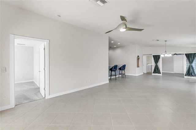 empty room featuring vaulted ceiling, ceiling fan with notable chandelier, and light tile patterned floors