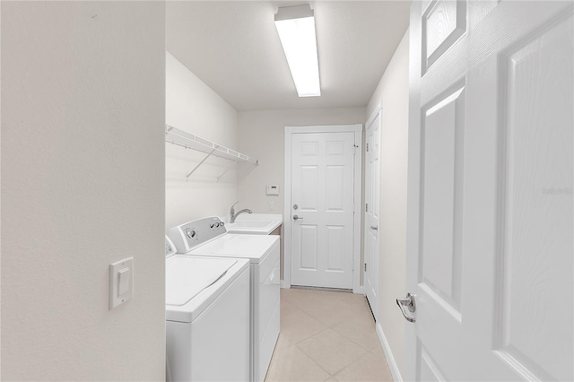 washroom with sink, light tile patterned floors, and washing machine and clothes dryer