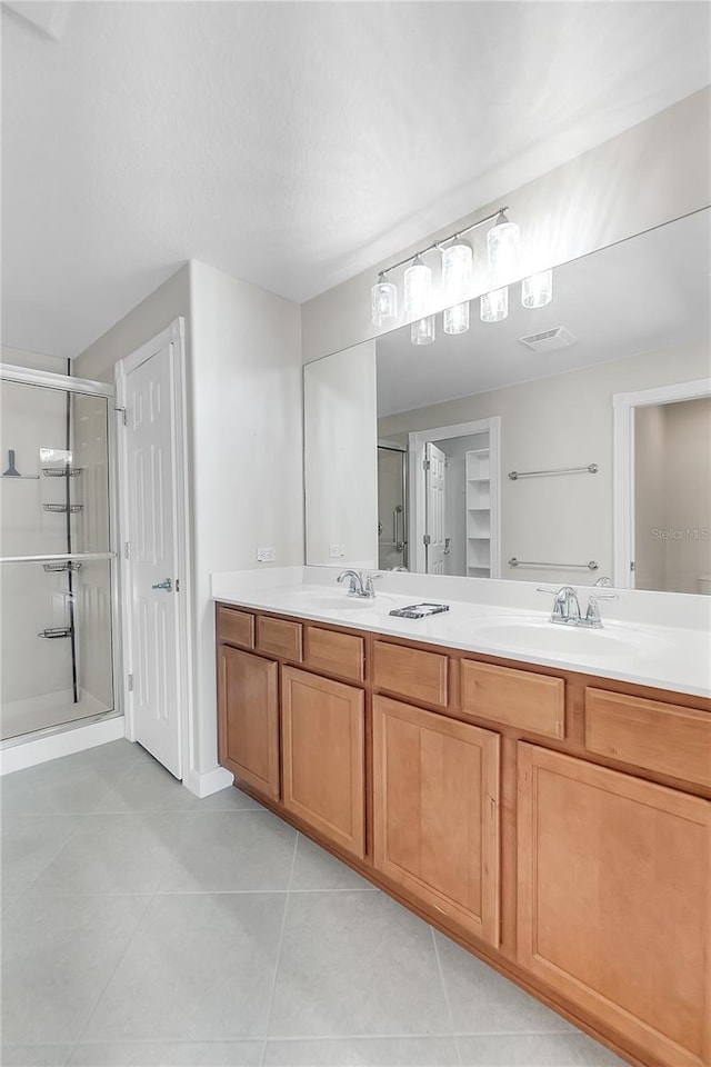 bathroom with a shower with door, vanity, and tile patterned flooring