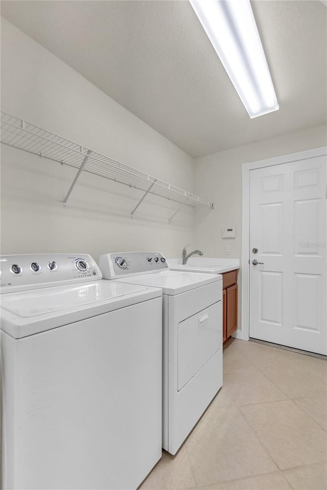 washroom with light tile patterned flooring, sink, cabinets, a textured ceiling, and washing machine and dryer