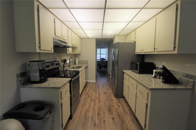 kitchen featuring sink, appliances with stainless steel finishes, white cabinetry, wood-type flooring, and light stone countertops