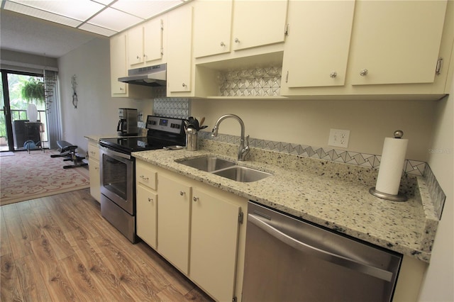 kitchen featuring sink, light hardwood / wood-style flooring, white cabinetry, stainless steel appliances, and light stone counters