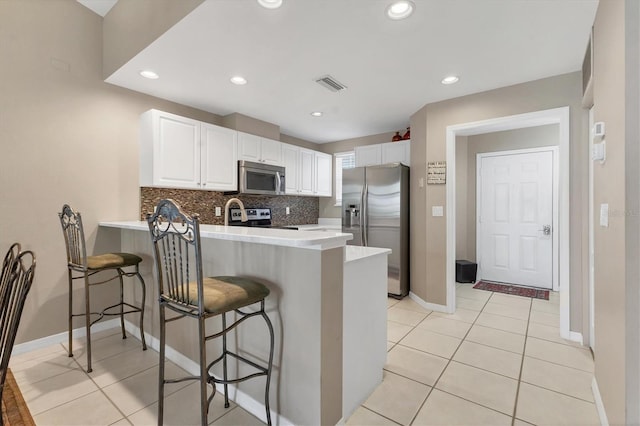 kitchen with visible vents, stainless steel appliances, a peninsula, white cabinets, and decorative backsplash