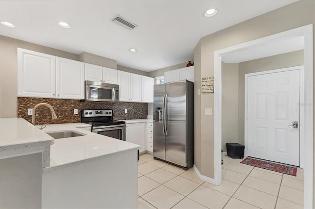 kitchen featuring a sink, a peninsula, light tile patterned flooring, and stainless steel appliances