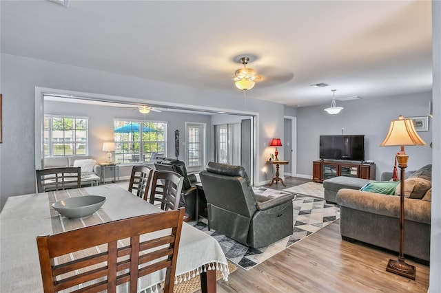 living room with light wood-type flooring, visible vents, baseboards, and a ceiling fan