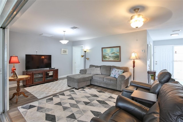 living room with visible vents, baseboards, and wood finished floors