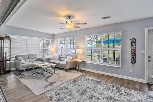 living room featuring visible vents, baseboards, and wood finished floors