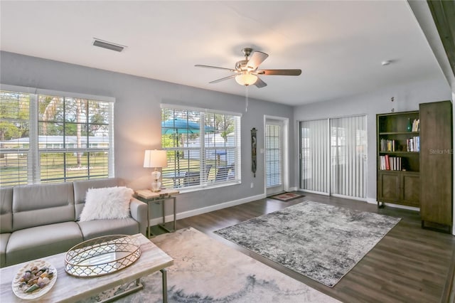 living area with dark wood-style floors, baseboards, visible vents, and a ceiling fan