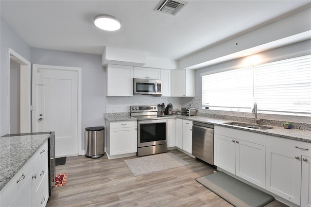 kitchen featuring visible vents, stainless steel appliances, light wood-style floors, white cabinetry, and a sink