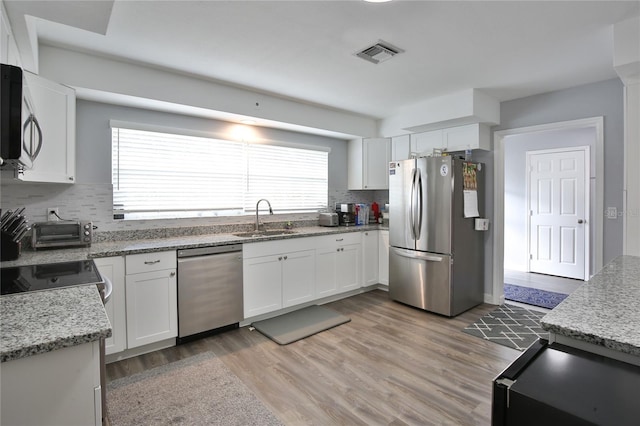 kitchen with stainless steel appliances, visible vents, a sink, and white cabinetry