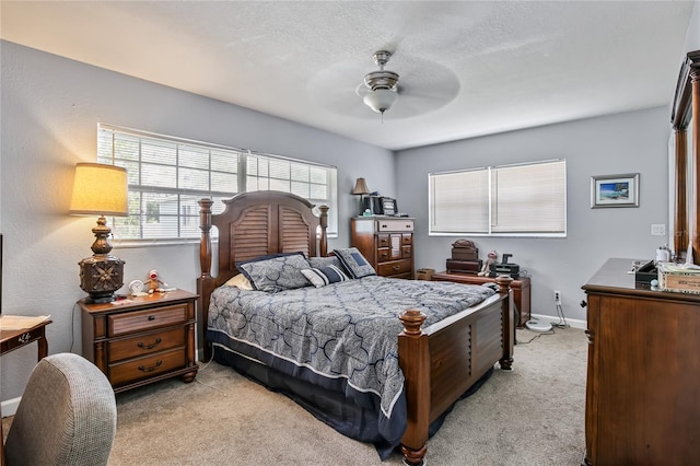 bedroom with ceiling fan, baseboards, a textured ceiling, and light colored carpet