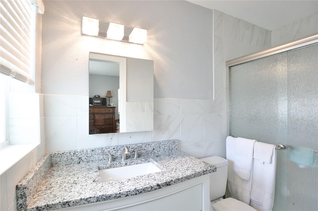 bathroom with toilet, a stall shower, tile walls, and vanity