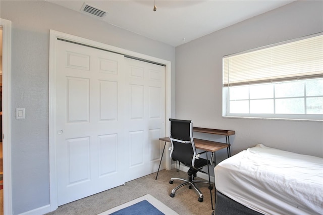 bedroom with carpet, visible vents, and a closet