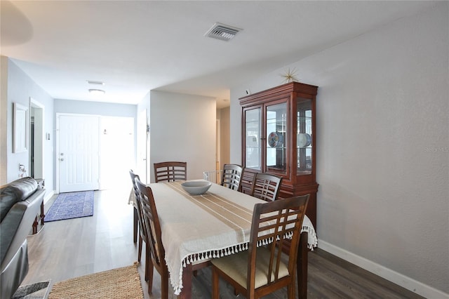 dining space with baseboards, visible vents, and wood finished floors