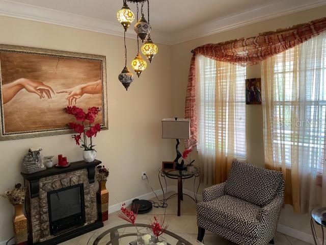 living area with crown molding and a stone fireplace