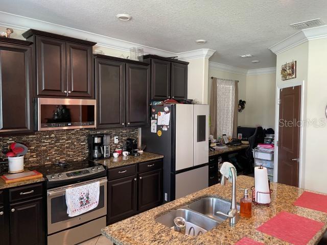 kitchen featuring sink, decorative backsplash, ornamental molding, and stainless steel appliances