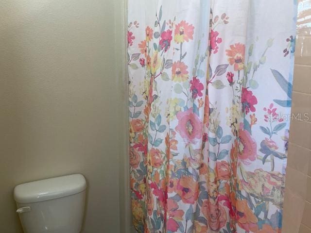 bathroom featuring toilet and curtained shower