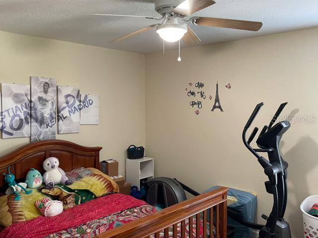 bedroom with ceiling fan and a textured ceiling