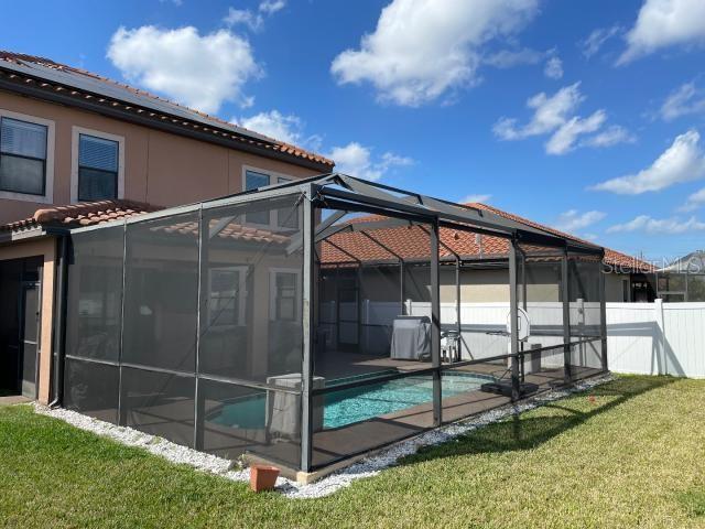 view of side of property with a fenced in pool, a lanai, and a yard