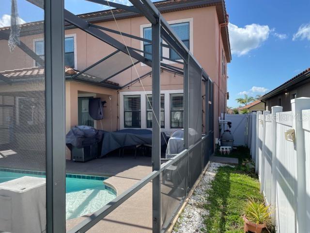 back of property with a fenced in pool, a lanai, and a patio area