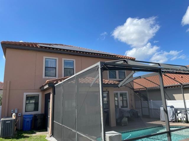 back of house with a fenced in pool, a patio area, glass enclosure, and central air condition unit