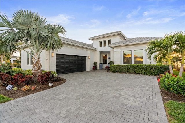 prairie-style house featuring a garage, decorative driveway, and stucco siding