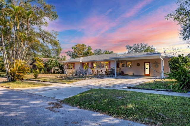 ranch-style house featuring a carport and a lawn