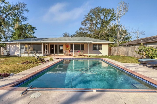 view of pool with a patio area, a sunroom, and a lawn