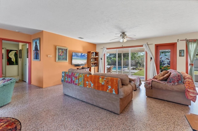 living room with ceiling fan and a textured ceiling