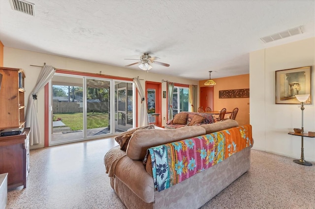 living room featuring ceiling fan, plenty of natural light, and a textured ceiling