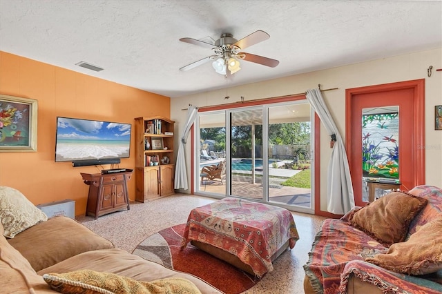 living room featuring ceiling fan and a textured ceiling