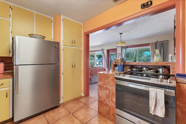 kitchen with light tile patterned flooring, appliances with stainless steel finishes, and hanging light fixtures