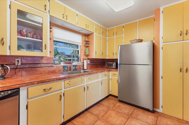 kitchen featuring sink, backsplash, stainless steel appliances, and light tile patterned floors