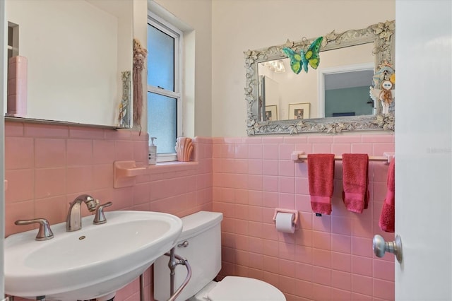 bathroom with toilet, sink, and tile walls