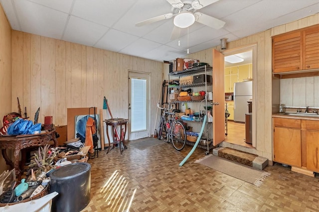 interior space with light parquet floors, sink, ceiling fan, and wood walls