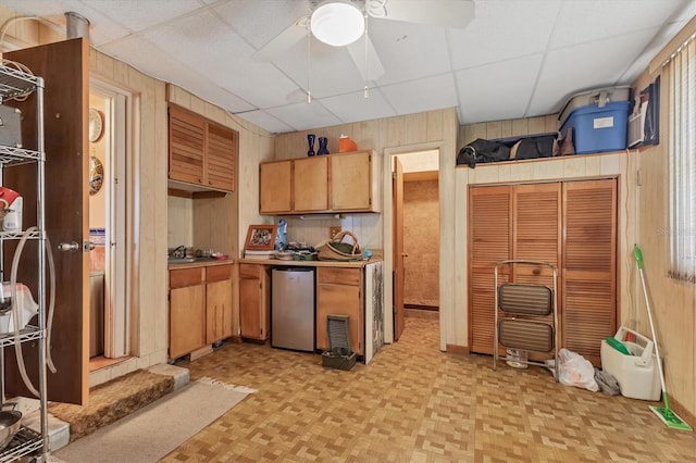 kitchen with a drop ceiling, fridge, light parquet flooring, and wood walls