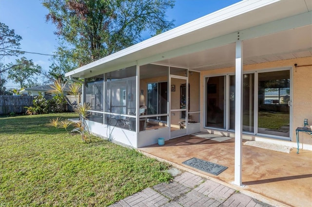 back of property with a yard, a patio area, and a sunroom