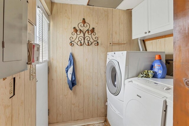 laundry area featuring cabinets, independent washer and dryer, wooden walls, and electric panel