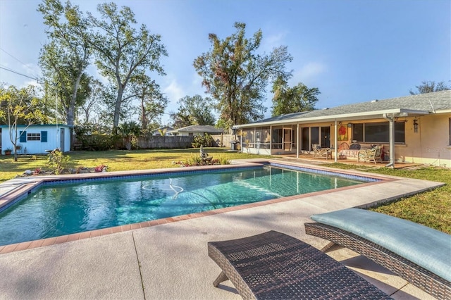 view of swimming pool with a sunroom, a yard, a patio area, and a storage unit