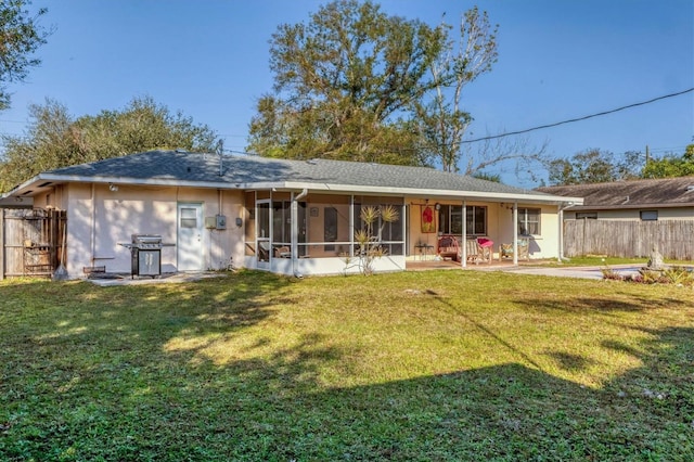 rear view of house featuring a lawn and a sunroom